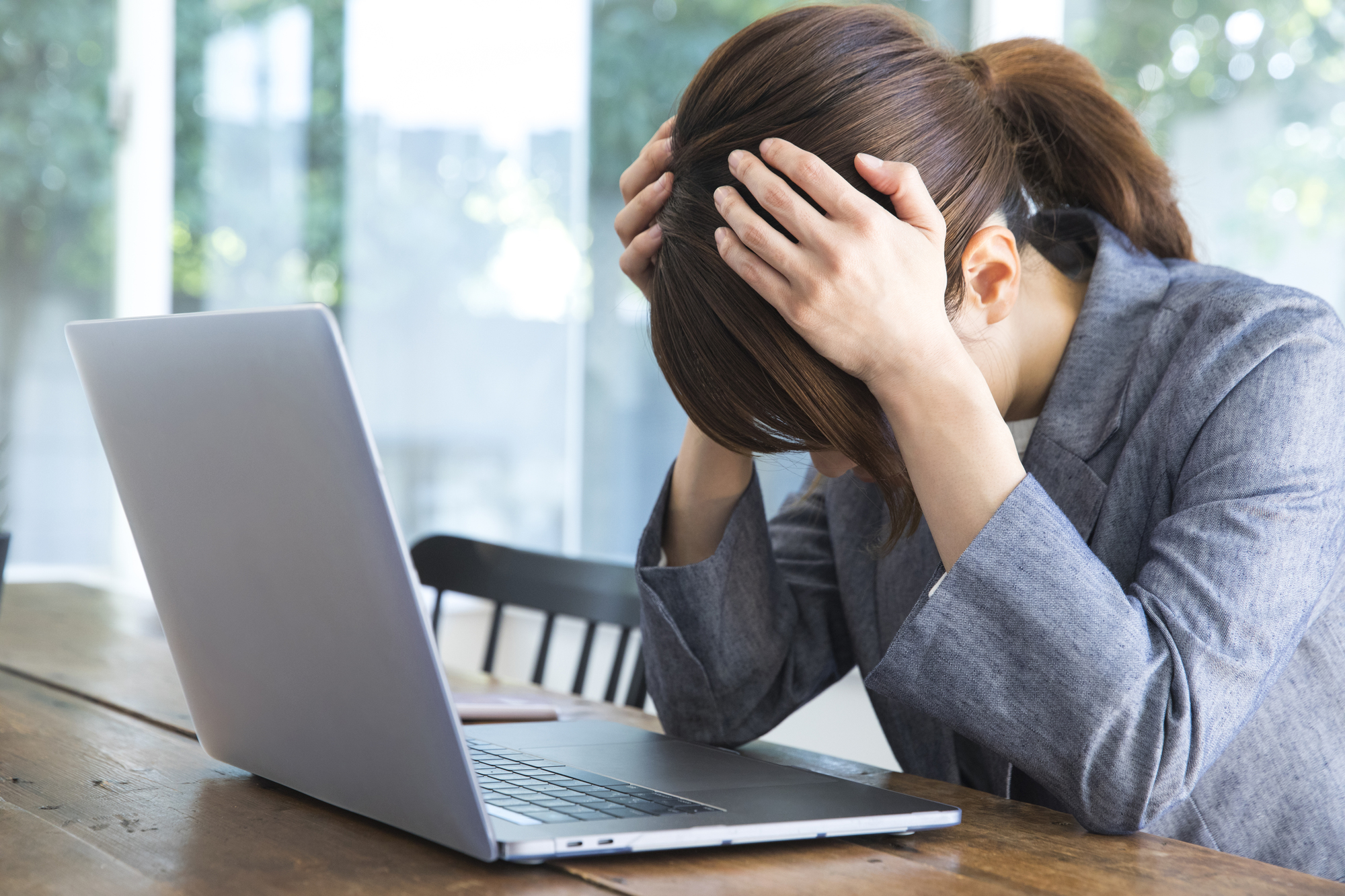 動画を見て、パソコンがウイルスに感染したと思って頭を抱える女性