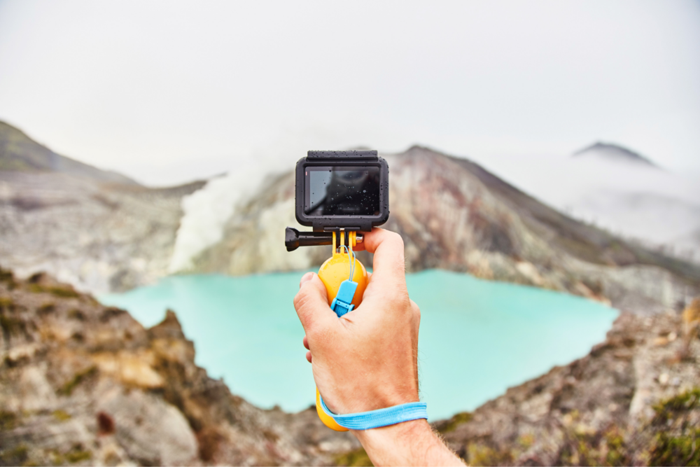 Goproで火山の火口を撮る男性の手元
