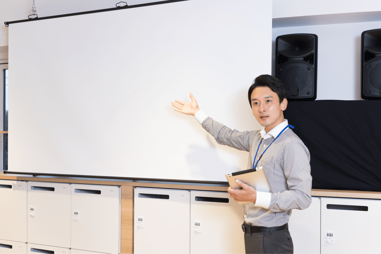 スクリーンの前でプレゼンをする男性