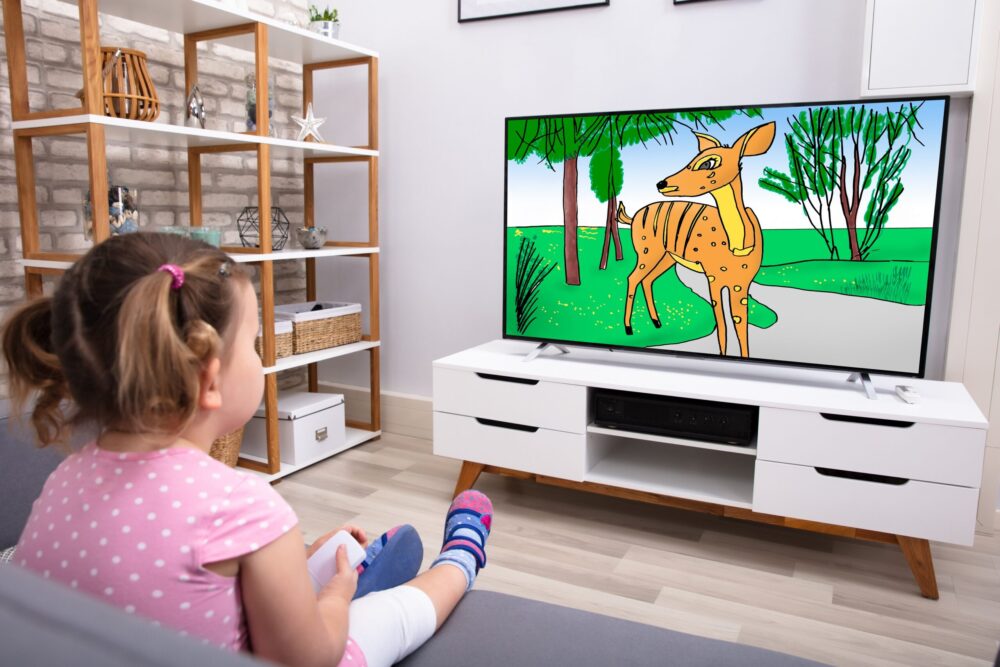 女の子が室内でソファに座りテレビを見ている