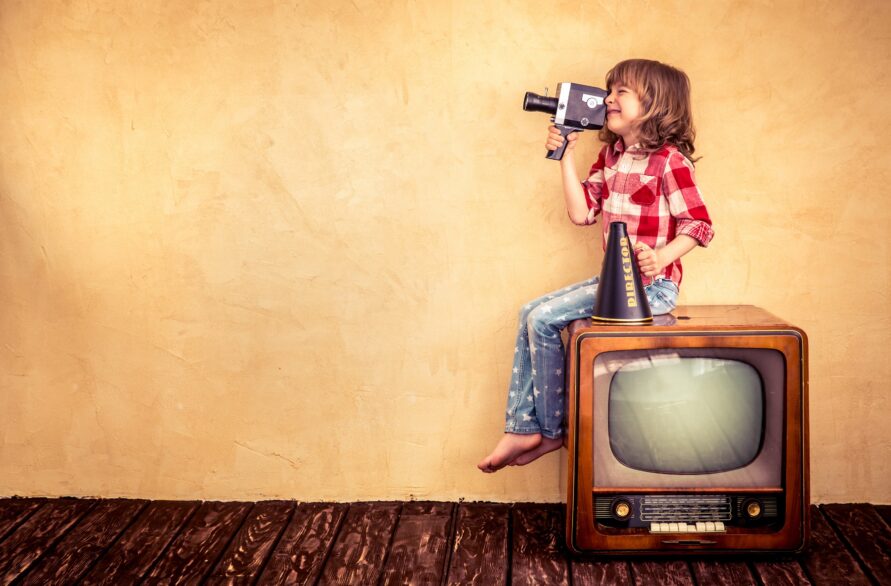 女の子がテレビの上に座りカメラを構えている