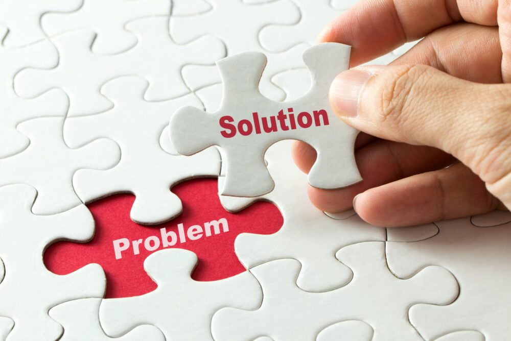 白いパズルを人が１つ掴みsolutionと書かれパズルを取った部分には赤に白文字でploblemと書かれている