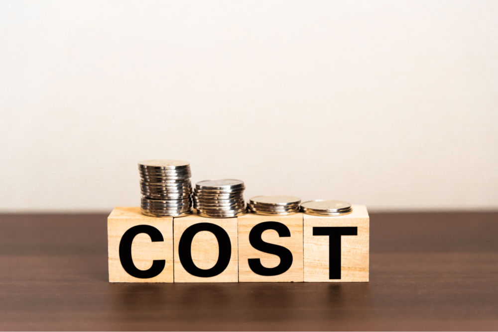 COSTと書かれた木のブロック、その上に乗る硬貨