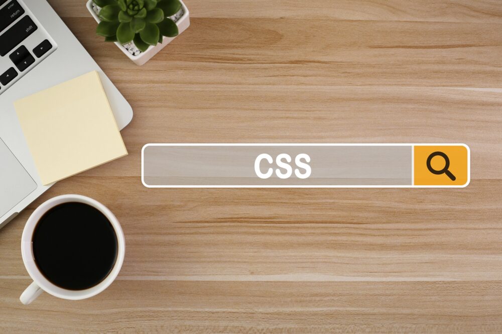 木目のデスクの上にPAとコーヒーが置かれ検索にCSSと入っている
