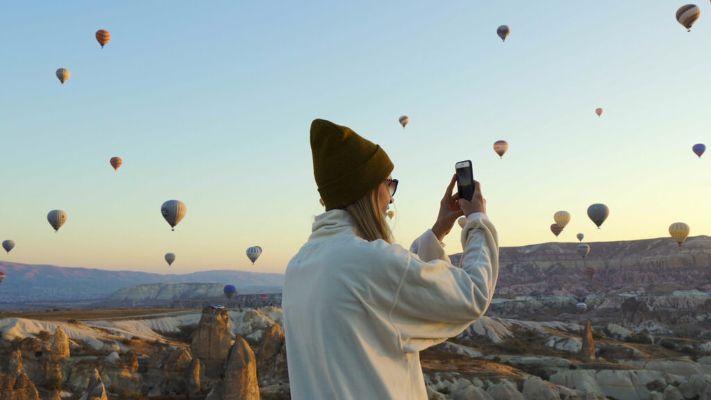 外でスマートフォンを構え写真を撮っている女性